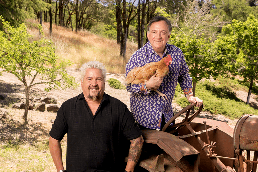 Guy Fieri and Robert Earl outside with a chicken